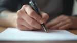 Image montrant une main écrivant avec un stylo sur une feuille blanche