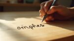 Une main écrivant le mot 'pensées' sur une feuille de papier.