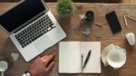 Bureau en bois avec ordinateur portable, cahier, stylo et objets décoratifs