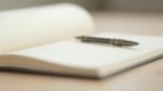 Cahier ouvert avec un stylo sur un bureau en bois clair